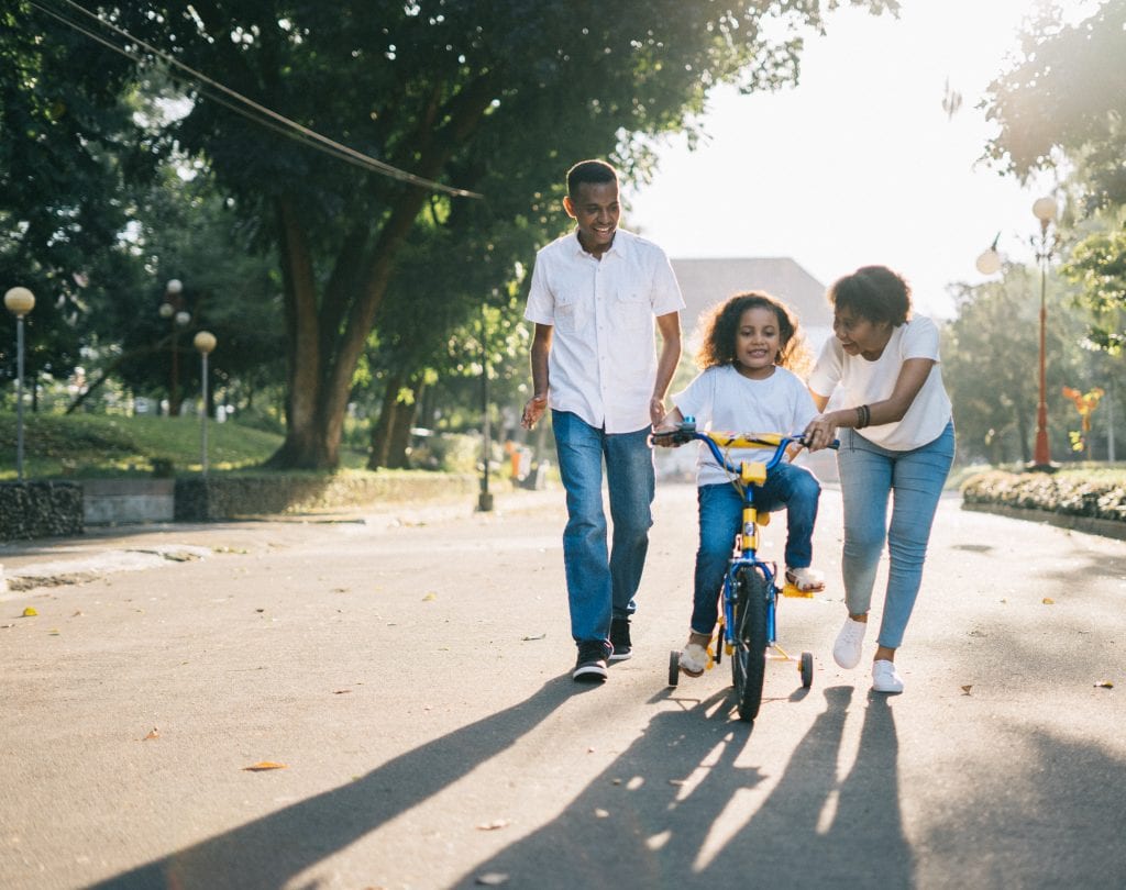 Child riding bike with her parents