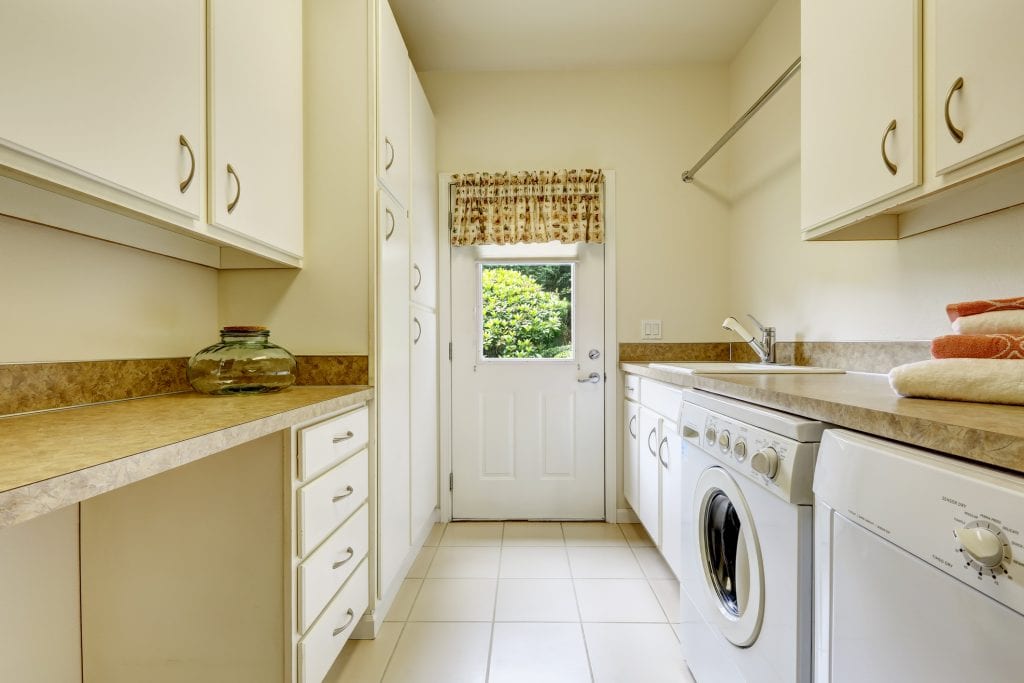 Bright laundry room with white cabinets and appliances